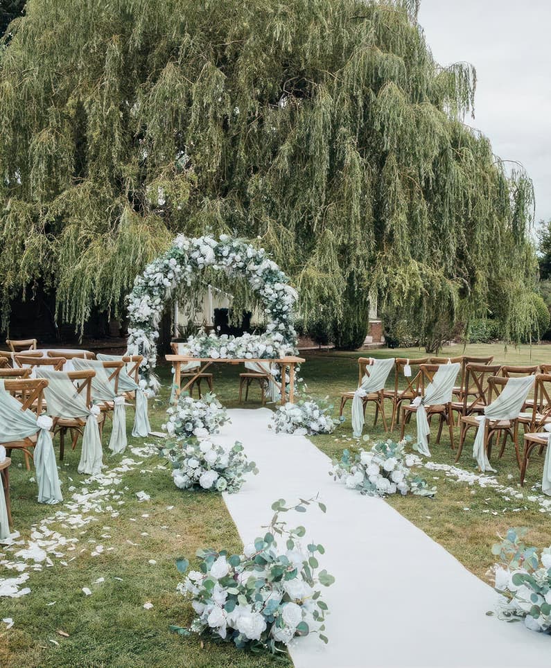 Hogarths Stone Manor outdoor wedding ceremony decor with floral arch, white aisle runner, eucalyptus flowers and draped chairs