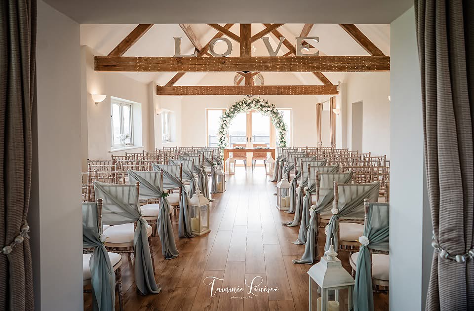 Sage green wedding aisle decor at Bordesley Park with chair drapes, lanterns and floral ceremony arch