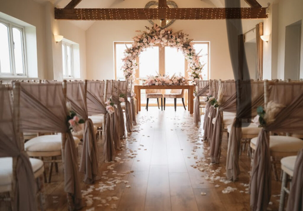 Blush wedding ceremony decor at Bordesley Park with chair drapes, petal aisle and floral arch backdrop