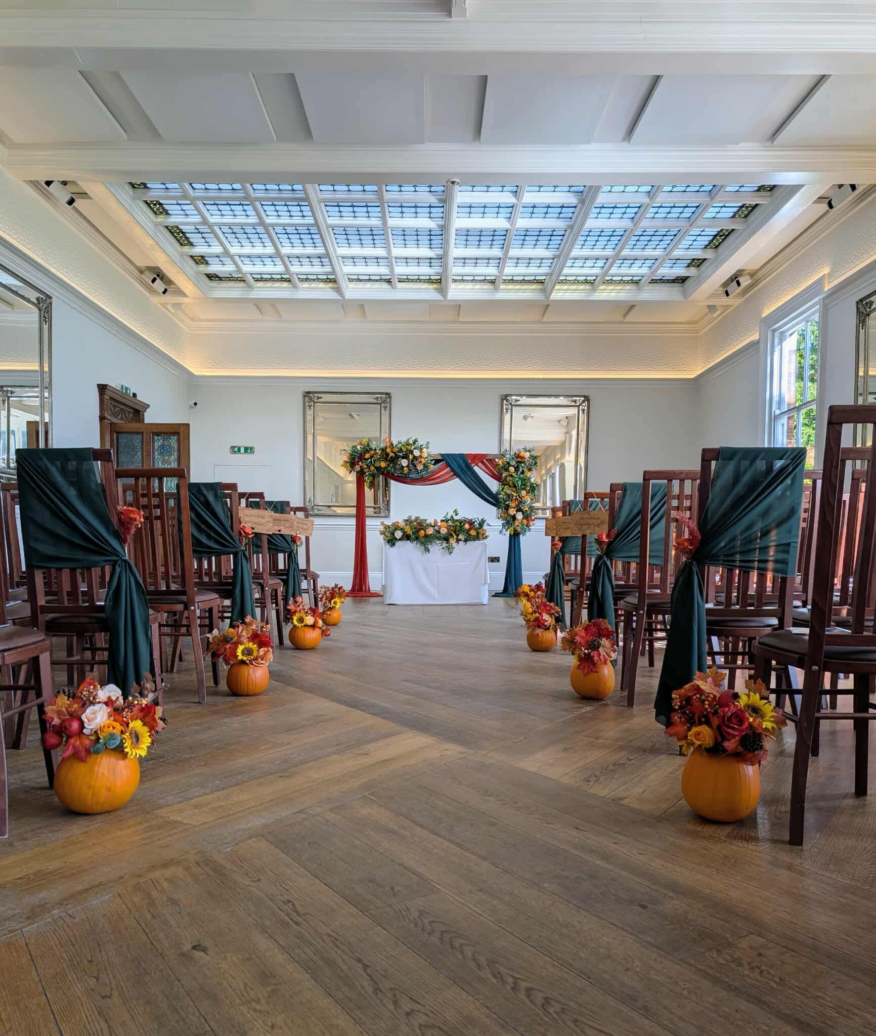 utumn wedding ceremony decor at Pendrell Hall with pumpkin floral arrangements, teal chair sashes and floral arch West Midlands