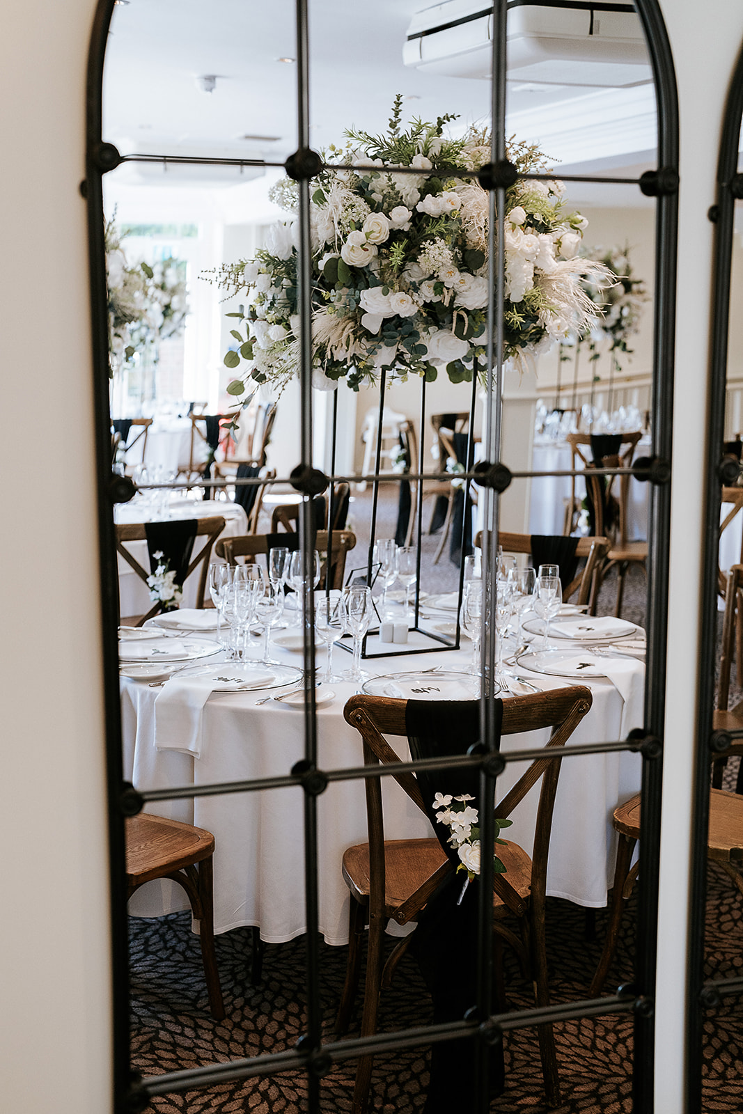 Elegant wedding table decorations with tall floral centrepiece using artificial wedding flowers, round guest table and wooden chairs at Hogarths Stone Manor — wedding decor hire Worcestershire.
