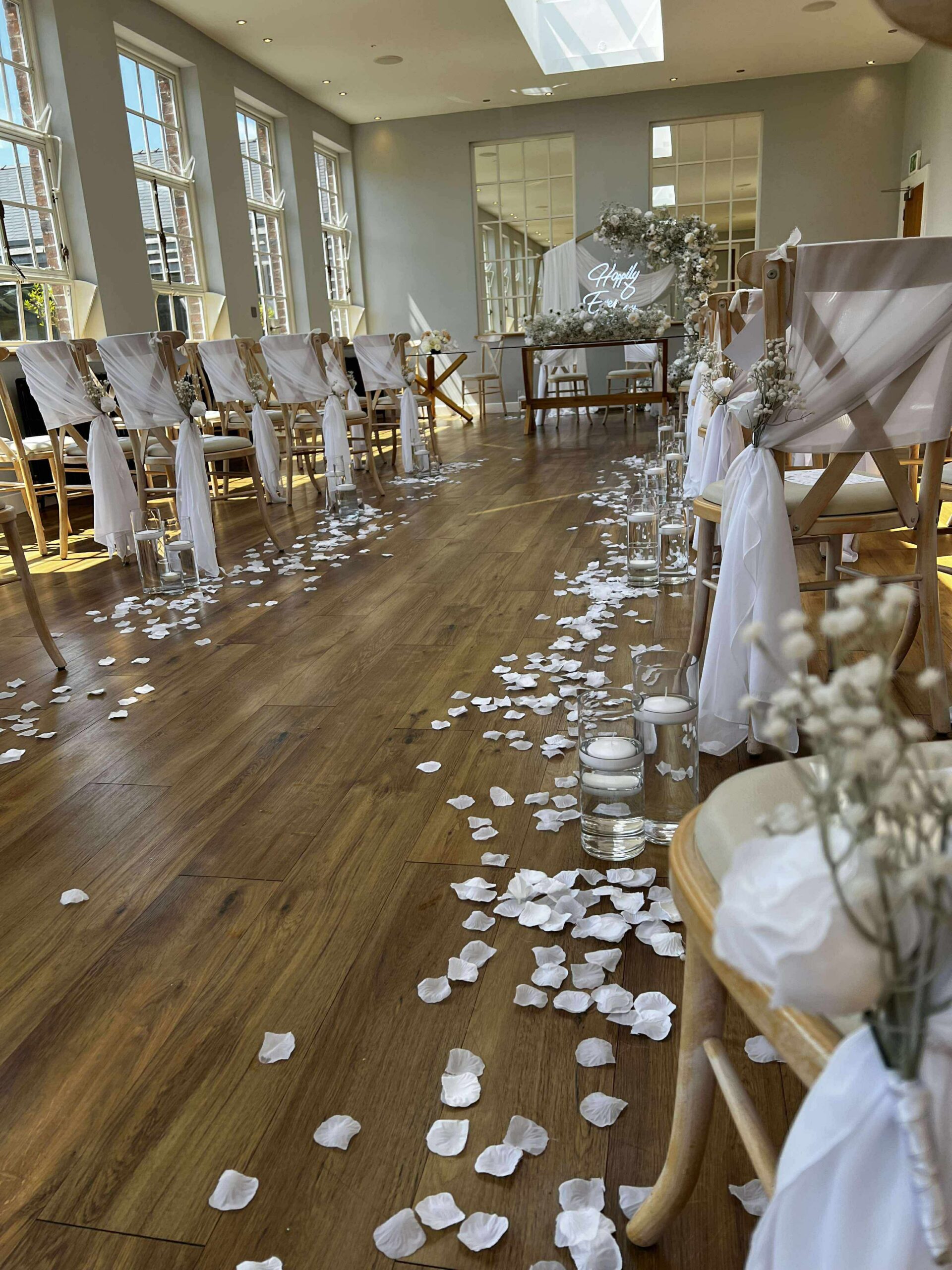 Wedding aisle with white petals candles and draped chairs at Bredenbury Court Barns ceremony setup