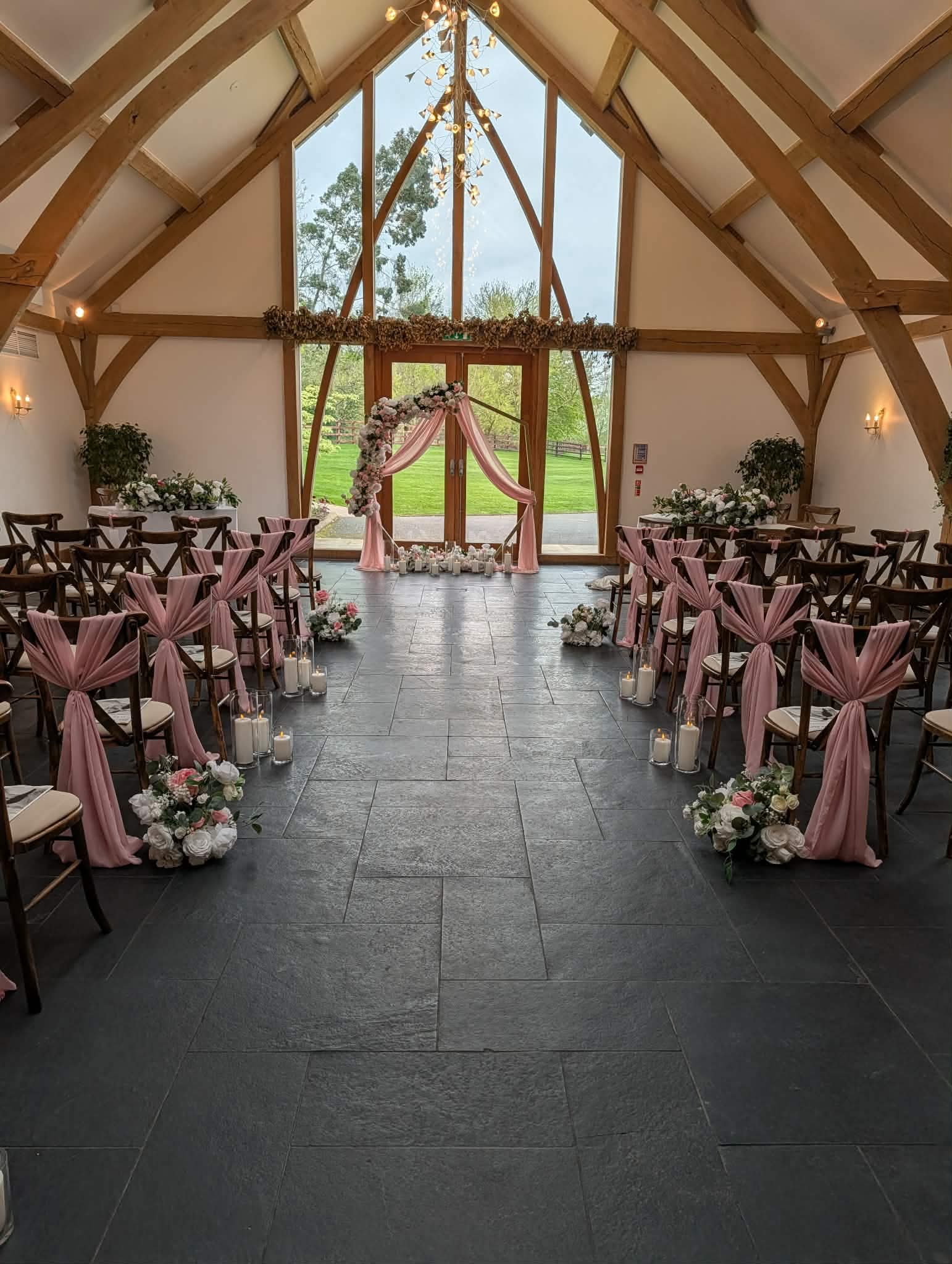 Wedding ceremony aisle with pink chair decor, candles and floral arrangements at Mythe Barn