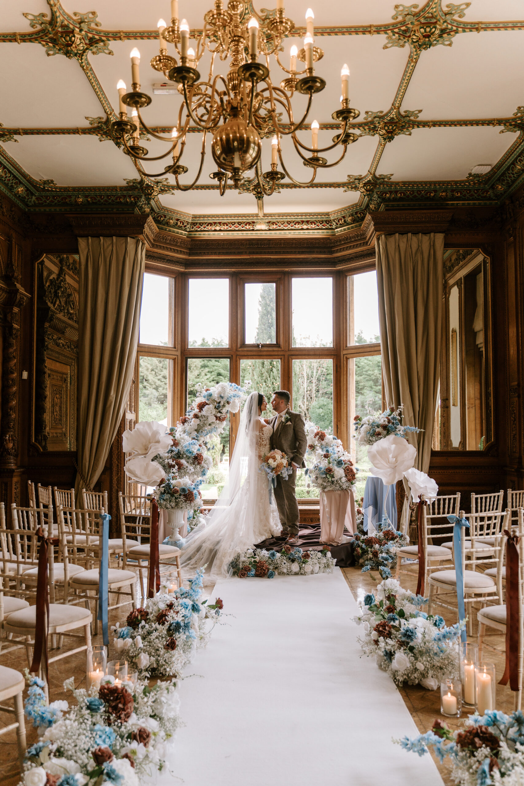 Wedding ceremony aisle with floral arch, white aisle runner and blue and brown decor at Manor By The Lake
