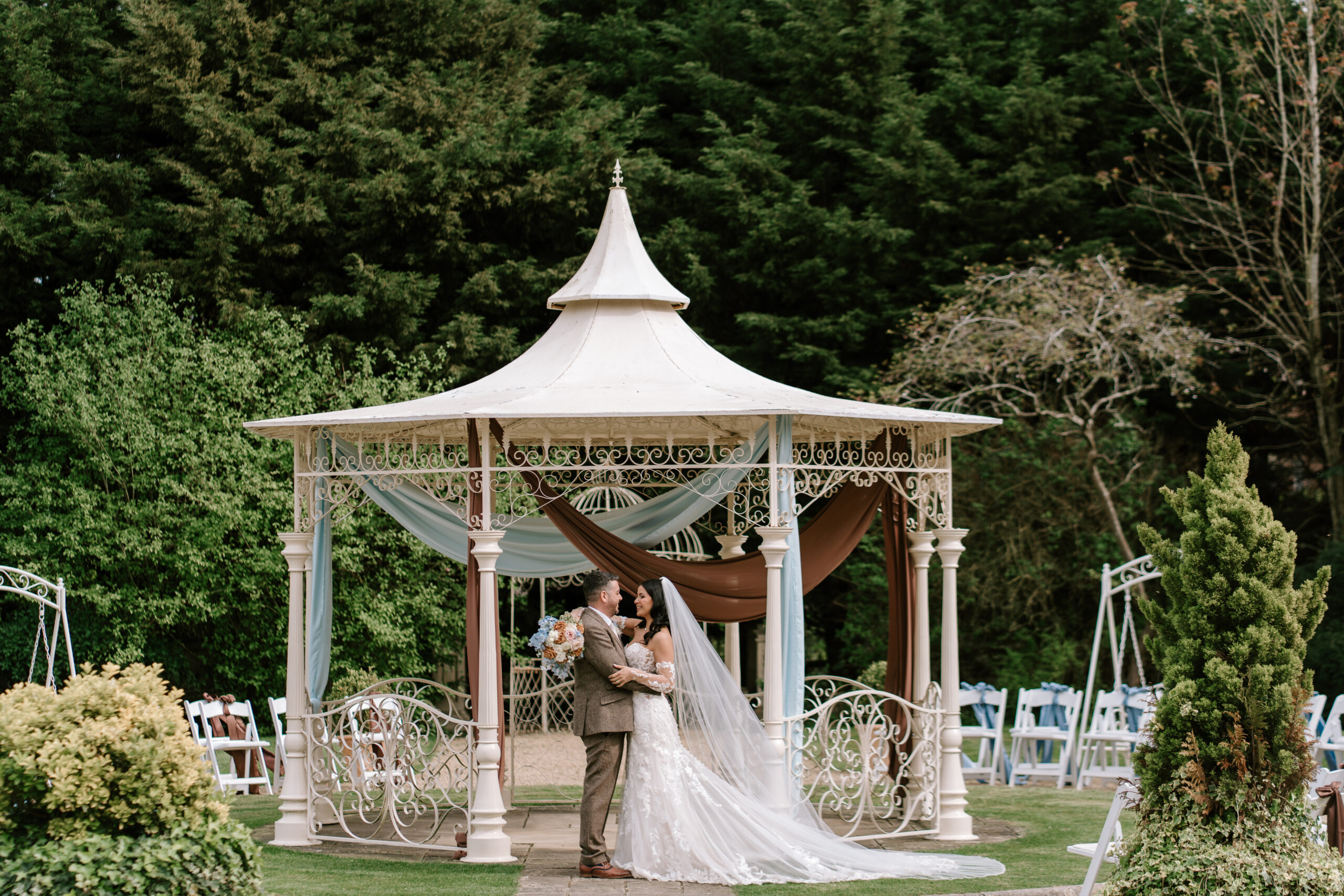 Outdoor wedding ceremony gazebo with blue and brown draping and couple at Manor By The Lake