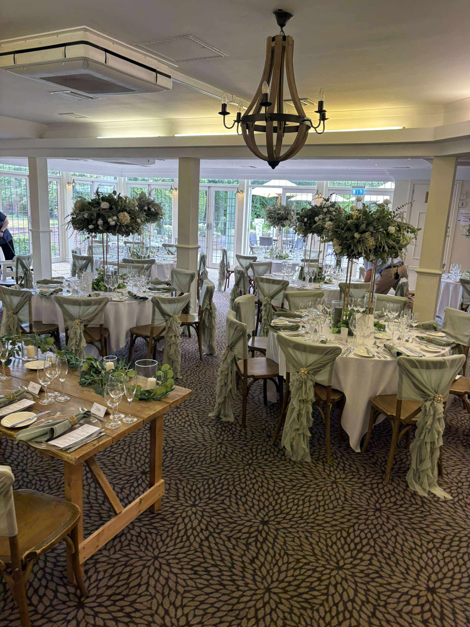 Sage green wedding reception decor with foliage centrepieces and chair draping at Stone Manor Hotel